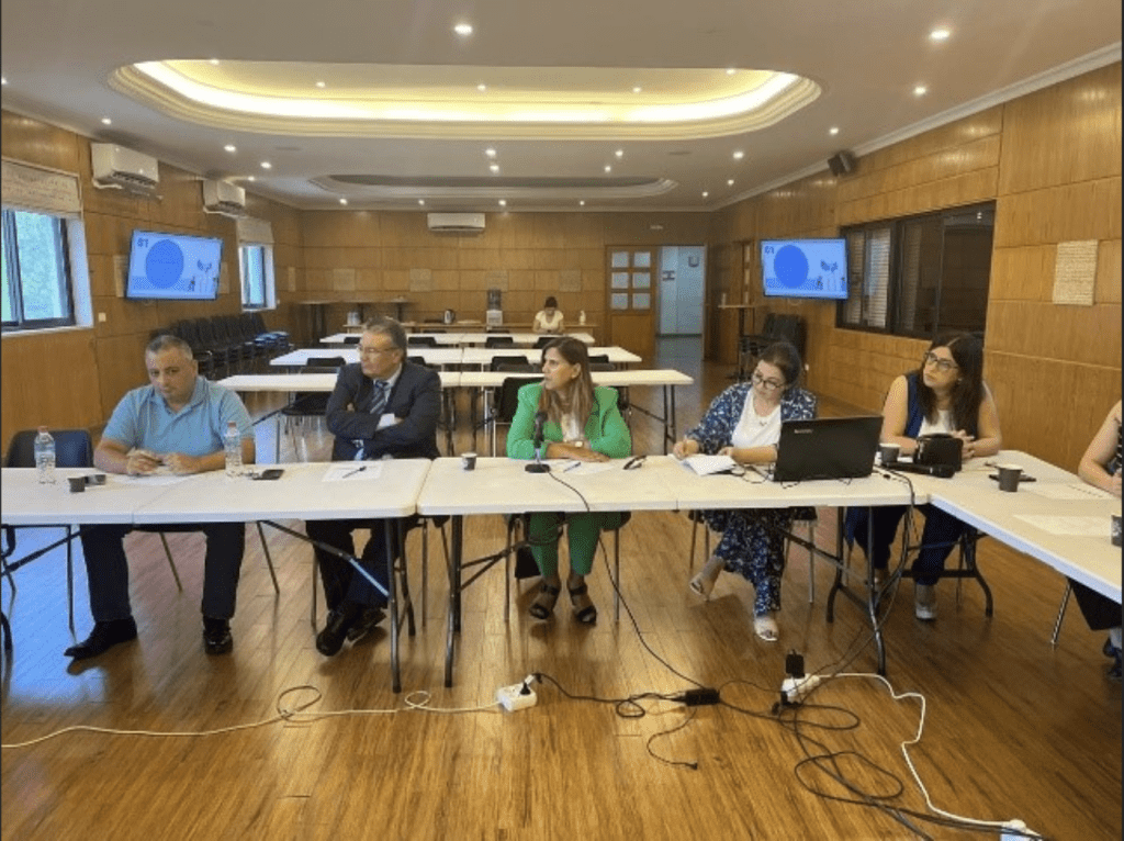 Group of individuals sitting at a table in a conference room, engaged in a meeting.